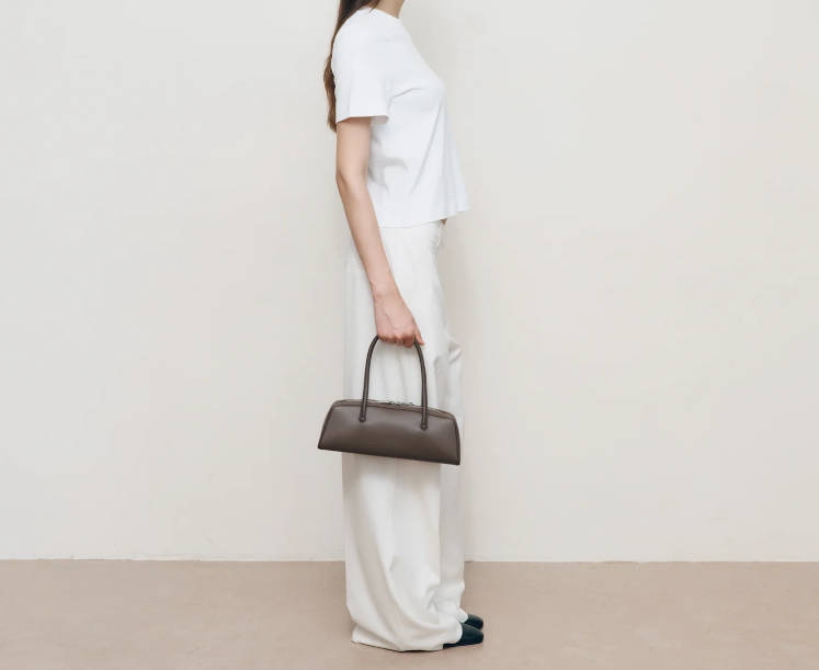 Mini‑Unterarmtasche aus glattem Leder mit dünnem gerolltem Griff und doppeltem Reißverschluss